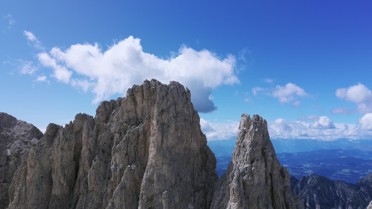 Majestic Vajolet Towers rock formation against clear blue sky with clouds, Catinaccio Group in Dolomites, Trentino, Italy