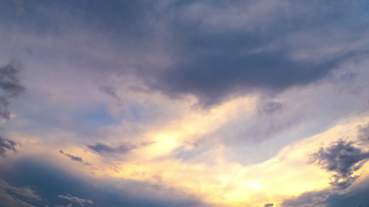 Beautiful sky lit with the setting sun. Clouds changing shapes and accumulating into dark cloudscape. Low angle view. Timelapse.