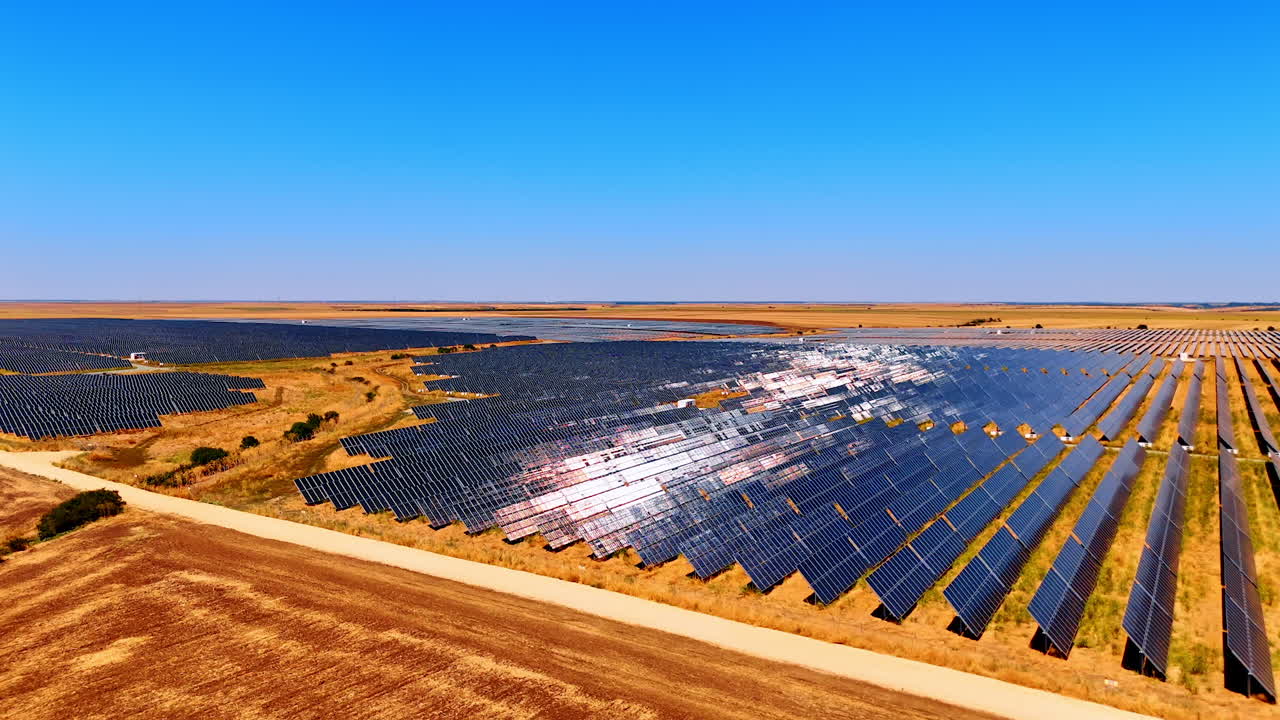 Solar farm landscape under clear sky. Expansive solar panels cover a dry landscape, generating renewable energy in a sunny, cloudless environment