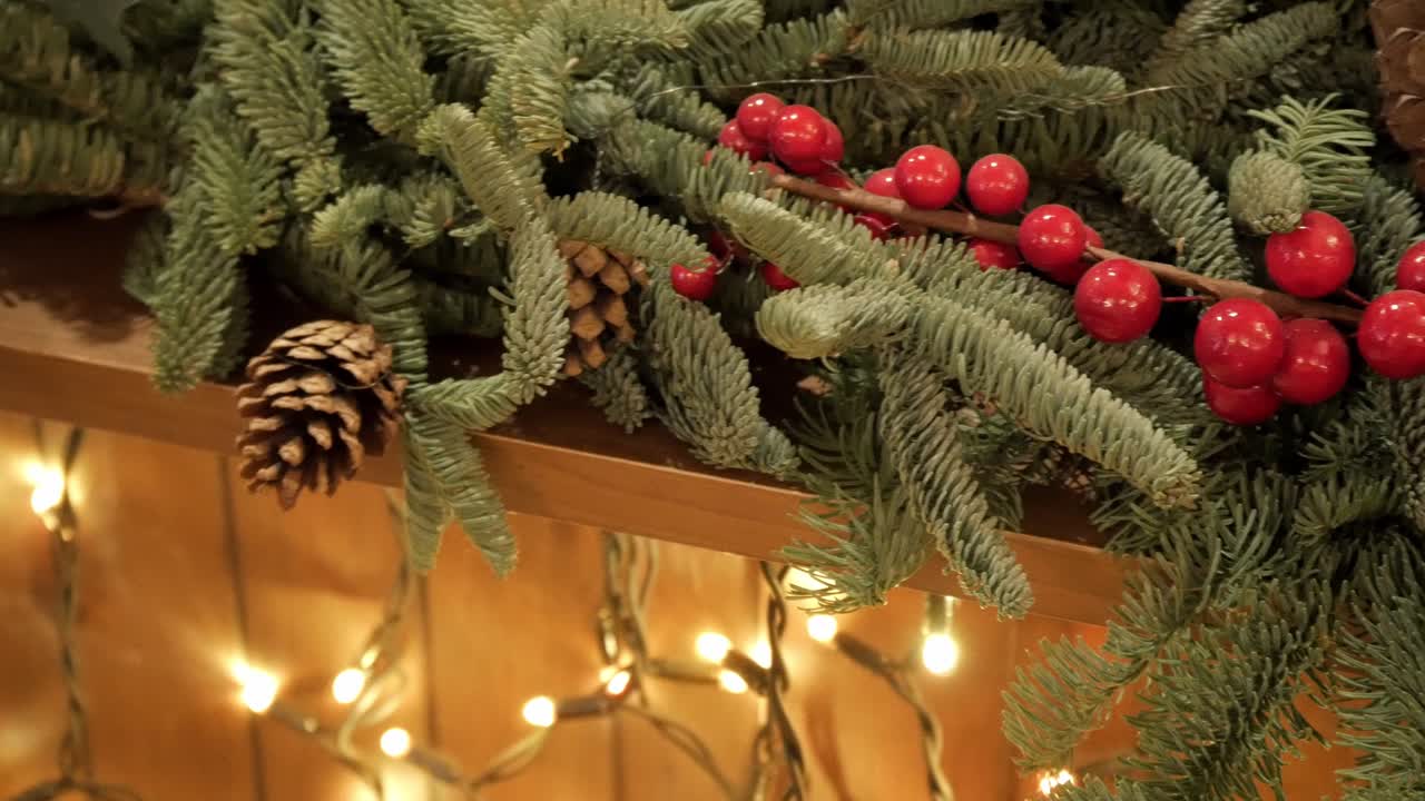Leftward path of Christmas decorations, pine branches with their fruits, pine cones, red spheres and white lights