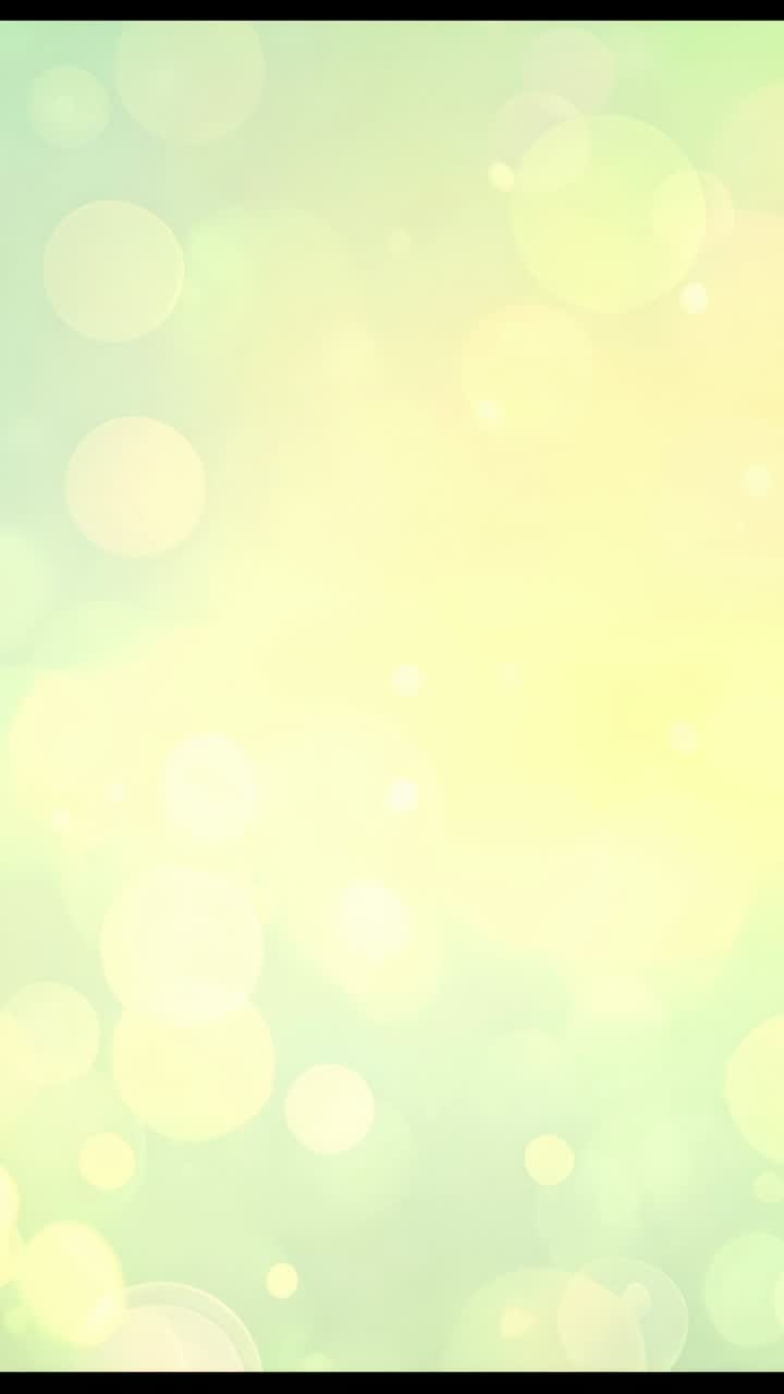 Vertical video: Following drifting bokeh circles, yellow orb expanding and receding across screen