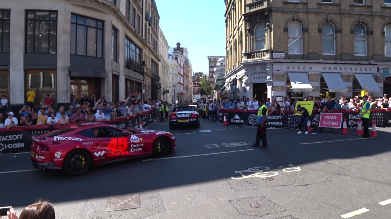 Security showing direction for luxury pimped cars during Gumball 300 Event in London. Beautiful sunny day and blue sky.