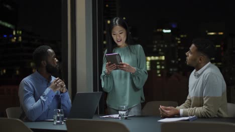 Video-of-asian-businesswoman-talking-to-two-diverse-male-colleagues-at-night-in-office-meeting