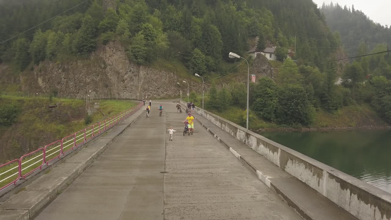 Drone shot of a small child with his father running along a damn bridge in rural Romania
