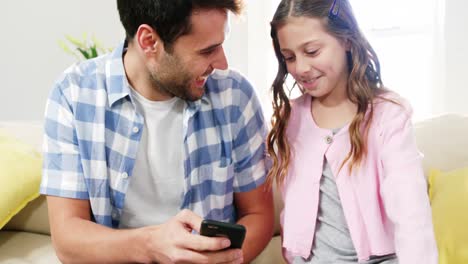 Vater-Und-Tochter-Benutzen-Mobiltelefon-Im-Wohnzimmer