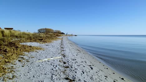 Clear-Skies-and-Rippling-Water-on-a-Calm-Baltic-Sea-Along-the-Shoreline-of-a-Beach-in-Kuznica,-Poland---Forward-Panning-Shot