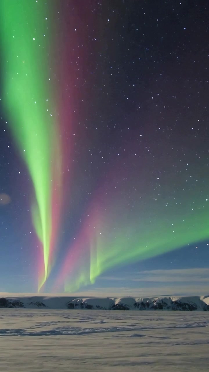 Video verticale: Cortine aurorali mutevoli che pulsano sull'orizzonte della notte polare, guidate dal vento solare.