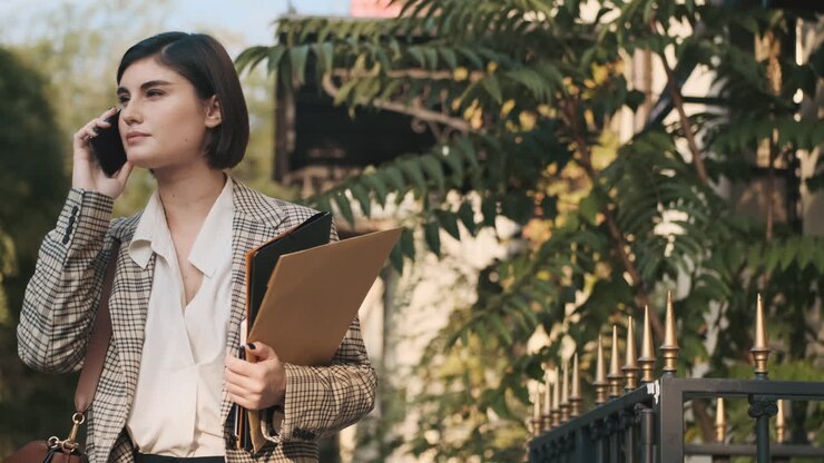 Donna elegante che effettua una chiamata di lavoro all'aperto