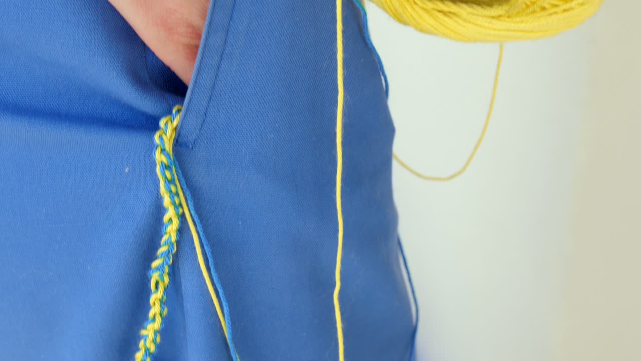 우크라이나 국기 색상을 보여주는 노란색과 파란색 뜨개질 원사가 있는 주머니에서 매달린 팔찌 실