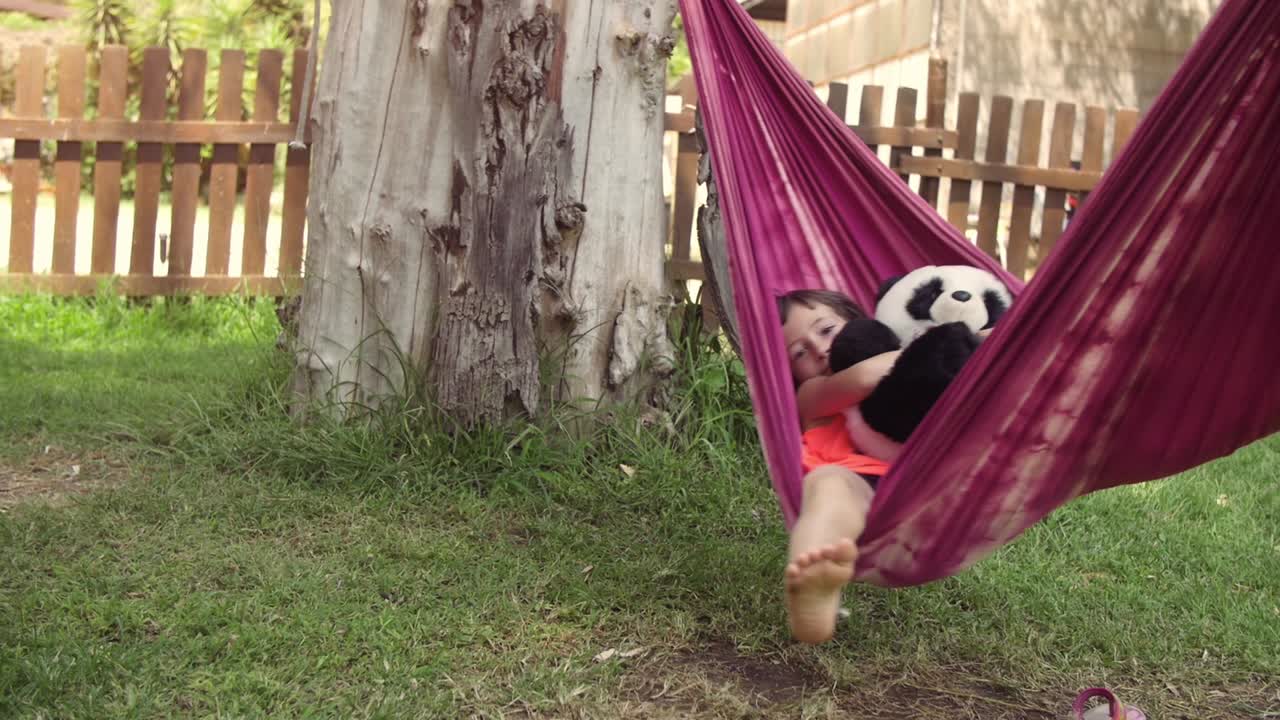 jóvenes niñas felices en el campamento de verano acostadas en hamacas coloridas relajándose jugando afuera con peluches muñecas de perro en el campo de hierba verde niños niños en cámara lenta