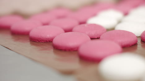 pink and white macarons on a baking sheet