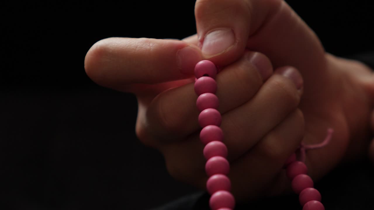 Close up shot of a Muslim prayer beads beads being used by a person while doing dhikr