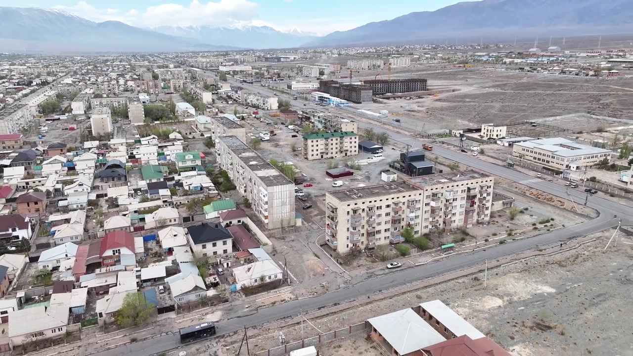 Sovyet dönemi apartman bloklarının üzerinde gri gökyüzü, Kırgızistan'ın Balykçı şehrinden bir sahne, dinamik drone çekimi