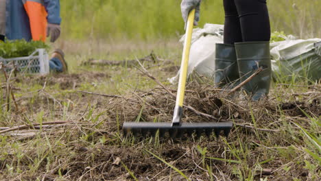 Vista-Cercana-De-Los-Pies-De-Un-Activista-Con-Botas-Y-Un-Rastrillo-Arando-La-Tierra-Para-Reforestar