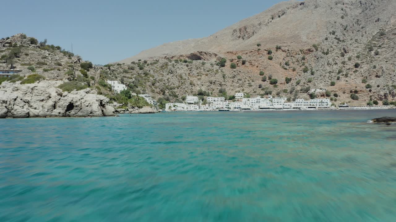 Aerial drone shot approaching coastal town quickly across the ocean