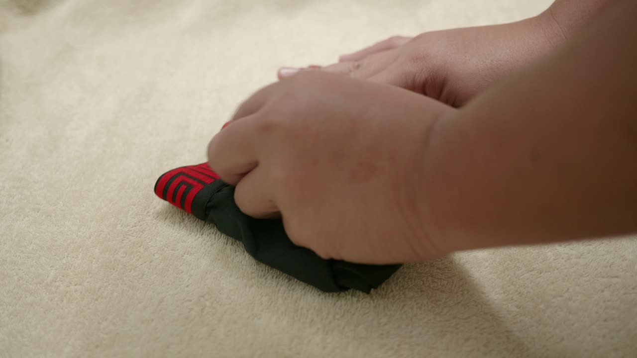 la mano del hombre está doblando el borde rojo de los hombres y la ropa interior de color negro para facilitar el almacenamiento en el viaje