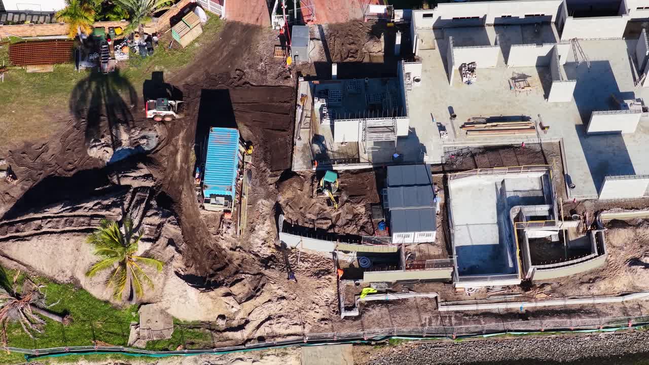 Drone footage captures construction progress on a luxury house by a canal in Gold Coast, Australia, under bright daylight
