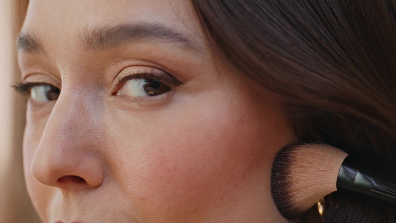 Closeup lady applying foundation using cosmetic brush at makeup preparation.