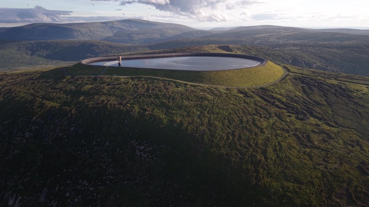 Panoramica aerea epica del bacino idrico di Turlough Hill al tramonto con le montagne di Wicklow sullo sfondo, Irlanda.