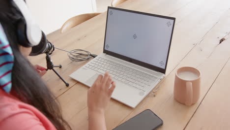 using laptop and microphone, asian woman recording podcast with coffee on table, at home, copy space