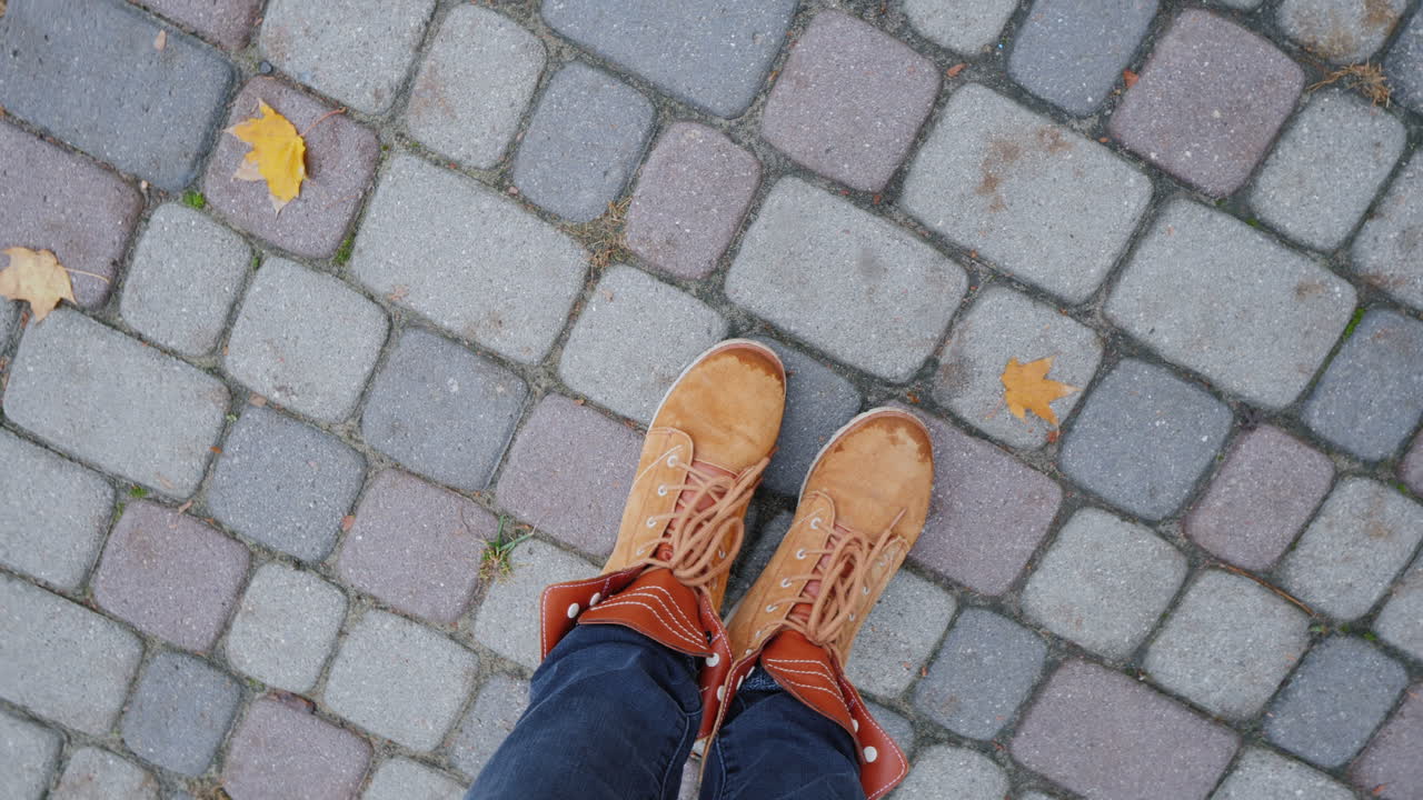 pies en botas de otoño en la acera la cámara gira