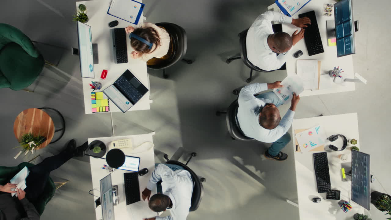 Top down view zoom out of staff in multinational company office reviews diagrams