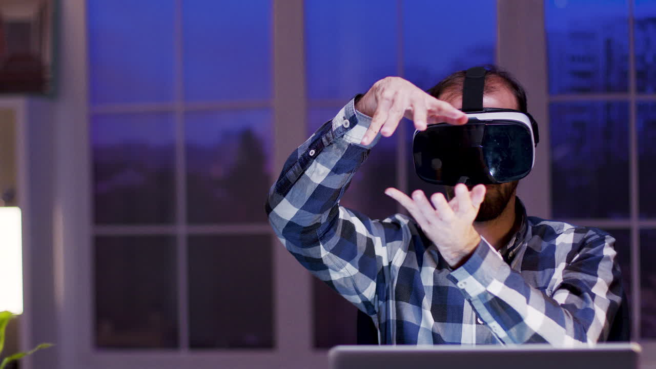 Man using VR headset with laptop at night