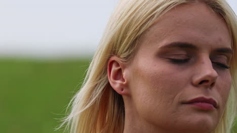 a young woman listens to birds sing while standing in a field or in a park