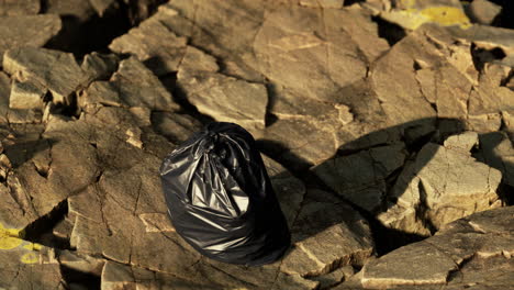 Ein-Schwarzer-Müllsack-Lag-An-Einem-Felsigen-Strand