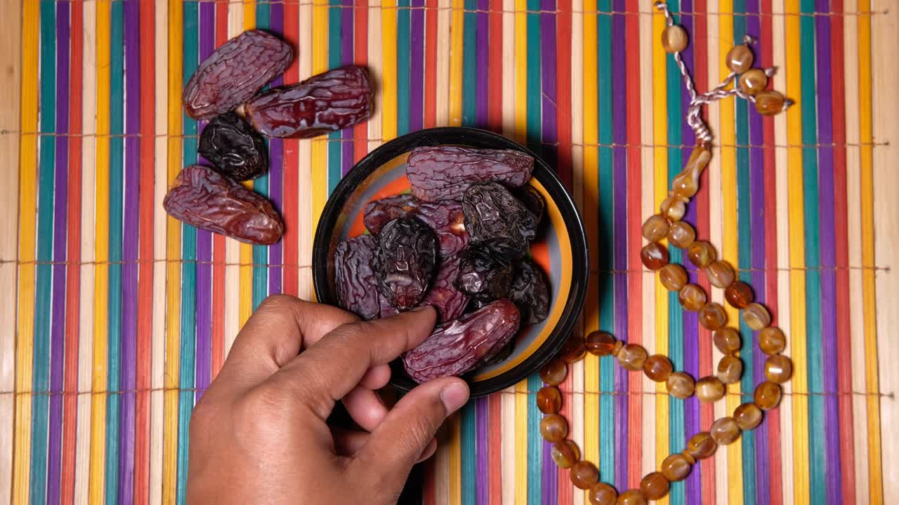 vista superior de la mano del hombre recogiendo frutas de dátiles de un cuenco