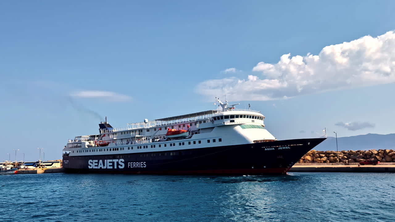 A large SeaJets ferry departs from the calm waters of Kissamos Port in Crete, Greece under a clear sky. Kissamos, Greece