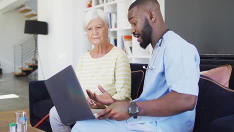 video of african american male doctor using laptop with caucasian senior woman