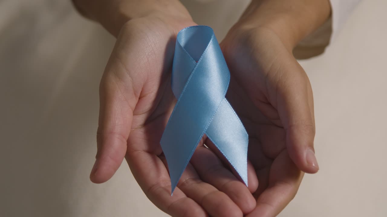 Close Up Of Person Holding Blue Ribbon Symbolizing Awareness Of Men's Health And Cancer 1