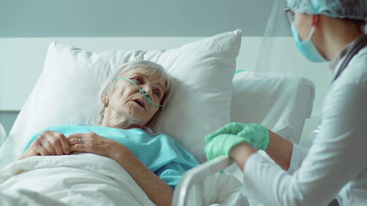 Donna anziana sdraiata sul letto d'ospedale che parla con l'infermiera