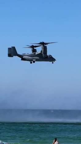 helicopter maneuvers over ocean, spraying water