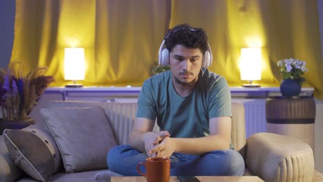 sad and unhappy man listening to music at night at home.