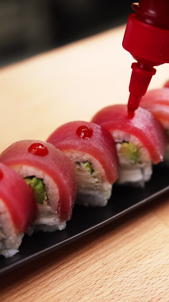 Salsa rossa che cola su involtini di sushi di tonno fresco.