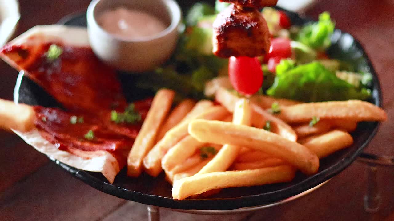 Hand reaching for fries on a food plate