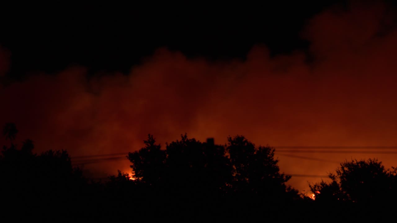 A large wildfire paints the horizon red and orange