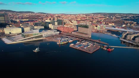 Aerial-drone-pan-shot-over-waterfront-buildings-along-the-seaside-in-Oslo,-Norway-during-morning-time