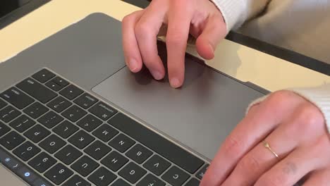 close up of caucasian adult hands typing on a macbook pro laptop keyboard