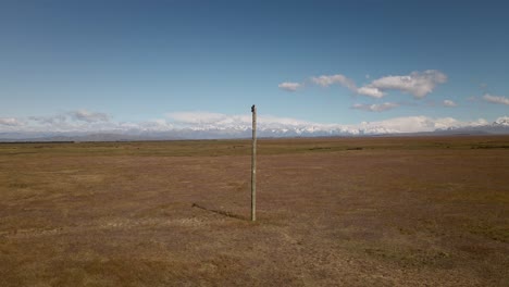 wooden power pole in front of majestic snow capped mountain range behind dry plains