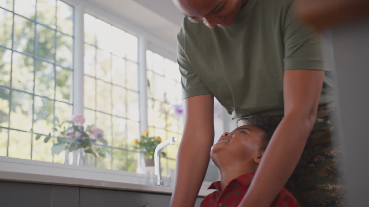 군복 을 입은 어머니 는 휴가 에 있는 집 에서 가족 의 부 에서 아들 과 함께 놀고 있다