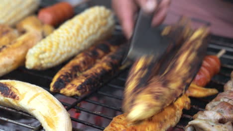 close up view of vendor slicing charcoaled banana on grill beside corn cob for customer in san cristobel in the galapagos