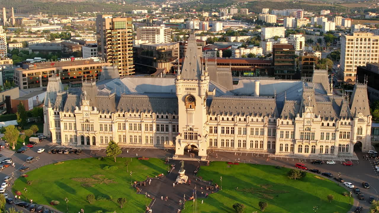 Aerial drone view of the Palace of Culture in Iasi downtown at sunset, Romania. Square with Stephen the Great statue, people and greenery in front of it, buildings around