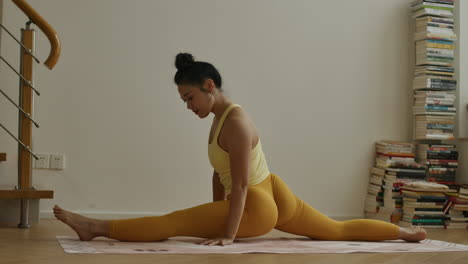 woman performing yoga splits at home