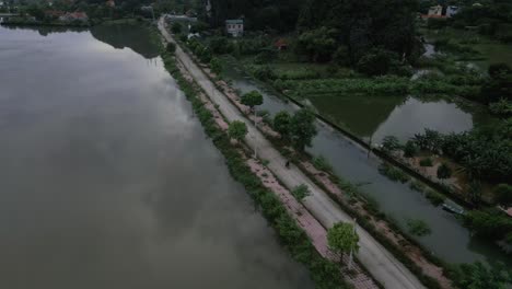 Aerial-shot-of-a-road-in-Asia-near-a-lake-and-mountains