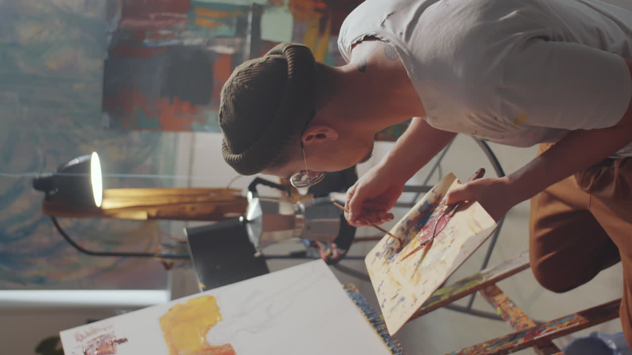 artista masculino pintando una imagen con pincel en lienzo