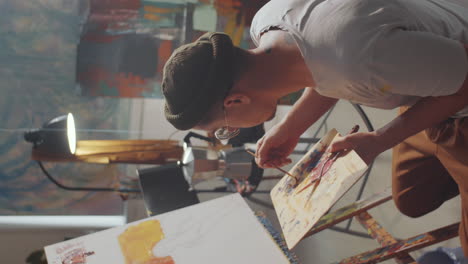 male artist painting picture with brush on canvas
