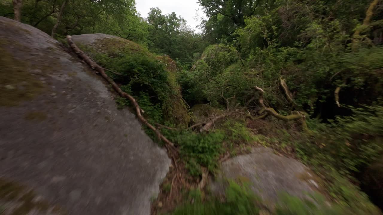 FPV drone gracefully descends to immerse into river, cutting through rocks